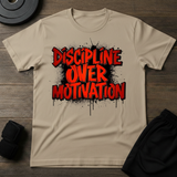 Discipline Over Motivation T-Shirt featuring bold graphic design in red and black on a tan background.